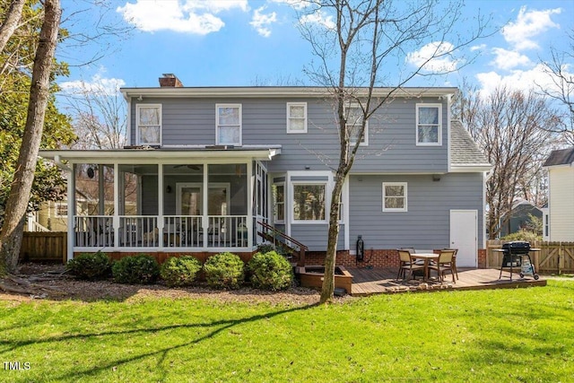 rear view of property featuring fence, a yard, a sunroom, a wooden deck, and a chimney