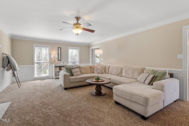 living area featuring a ceiling fan, carpet, a wainscoted wall, and ornamental molding