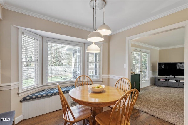 dining space with radiator, crown molding, and wood finished floors