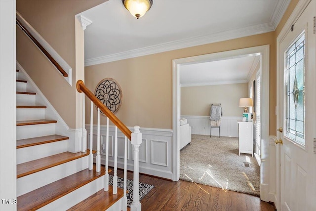 foyer entrance featuring wainscoting, crown molding, a healthy amount of sunlight, and wood finished floors