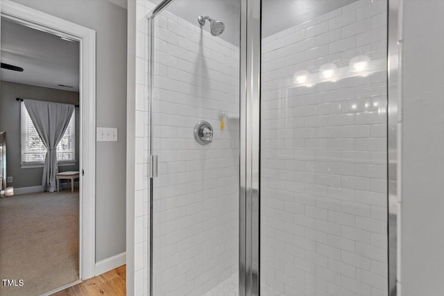 full bath with wood finished floors, baseboards, and a stall shower