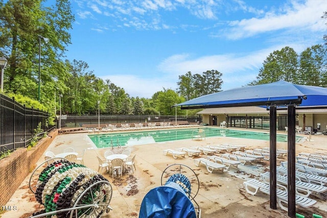 community pool with a patio and fence