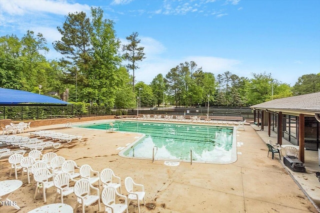 community pool with a patio and fence