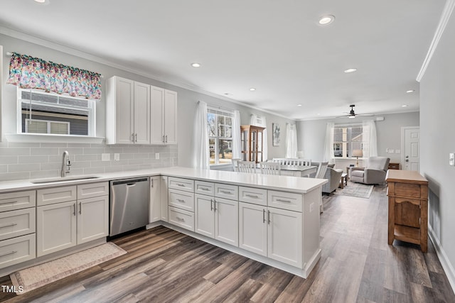 kitchen featuring a sink, dark wood finished floors, light countertops, a peninsula, and stainless steel dishwasher