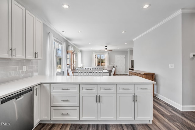 kitchen with a peninsula, decorative backsplash, light countertops, stainless steel dishwasher, and crown molding