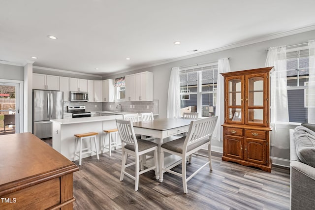 dining room featuring crown molding, recessed lighting, wood finished floors, and a healthy amount of sunlight