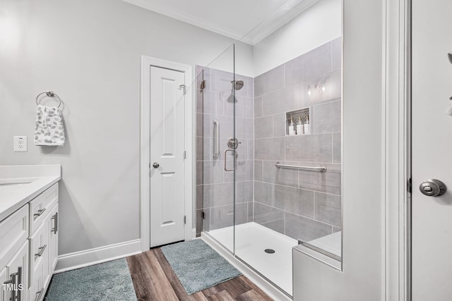 bathroom with a shower stall, baseboards, ornamental molding, wood finished floors, and vanity