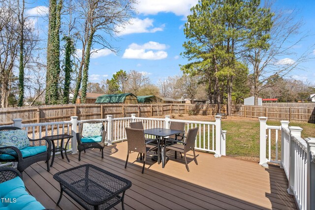 wooden terrace featuring outdoor dining area, a lawn, and a fenced backyard