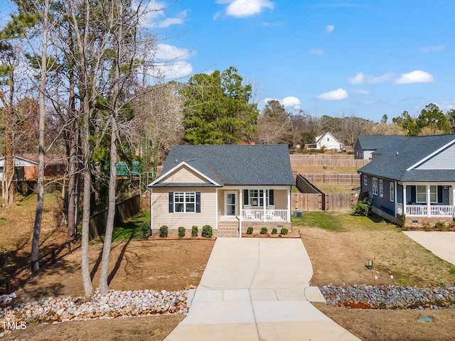 view of front of property with a front yard, fence, covered porch, and a shingled roof