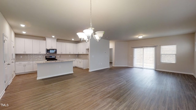 kitchen featuring wood finished floors, white cabinets, appliances with stainless steel finishes, open floor plan, and backsplash