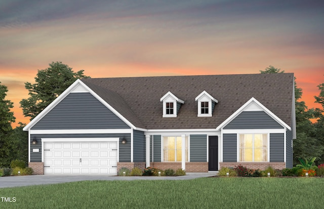 cape cod-style house featuring brick siding, a yard, a garage, and driveway