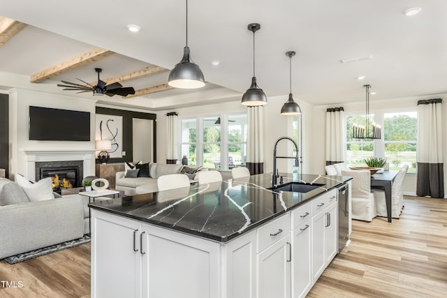 kitchen featuring a sink, open floor plan, light wood-style floors, and an island with sink