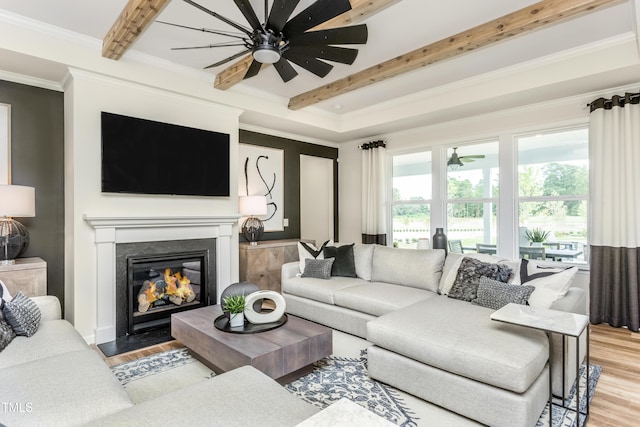 living room featuring a fireplace with flush hearth, light wood-style floors, beam ceiling, and ornamental molding