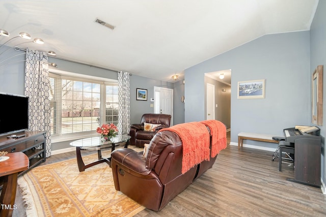 living room with visible vents, wood finished floors, baseboards, and vaulted ceiling