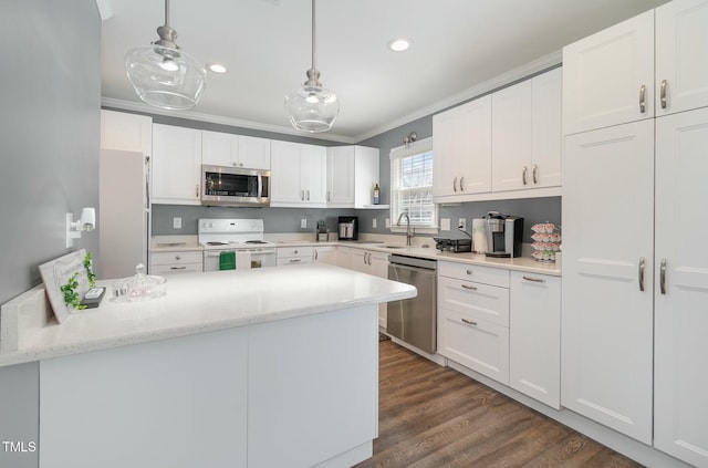 kitchen with a sink, dark wood finished floors, appliances with stainless steel finishes, white cabinets, and crown molding