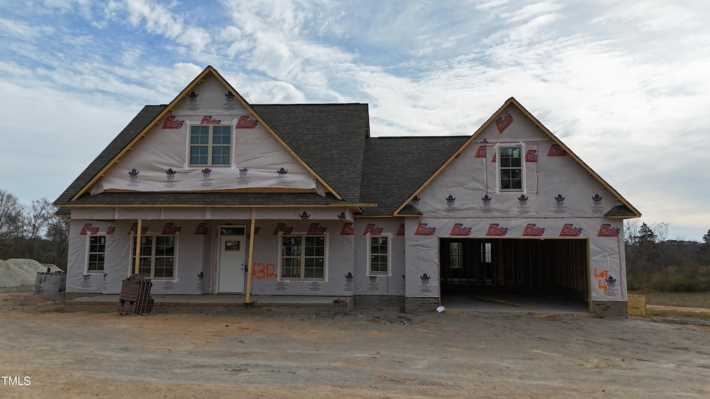 property under construction with a garage, roof with shingles, and covered porch