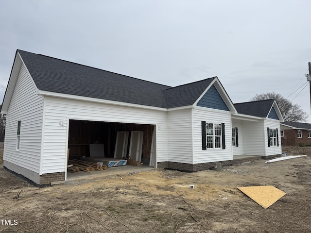 exterior space with a garage and roof with shingles