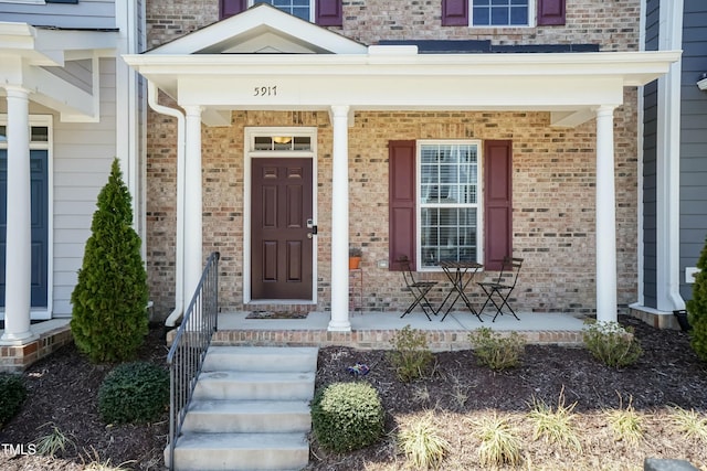 entrance to property featuring brick siding and covered porch