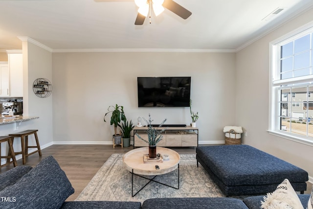 living room with visible vents, ornamental molding, baseboards, and wood finished floors