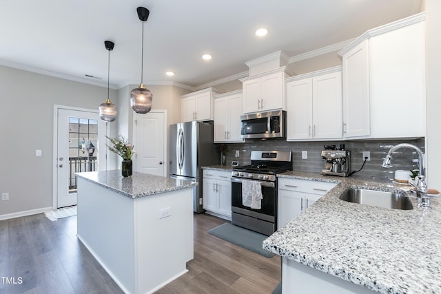 kitchen featuring wood finished floors, a kitchen island, a sink, stainless steel appliances, and tasteful backsplash