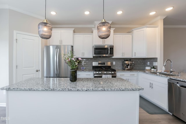 kitchen with a sink, crown molding, a kitchen island, and stainless steel appliances