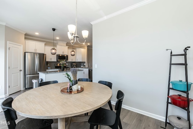 dining room with baseboards, an inviting chandelier, wood finished floors, and crown molding