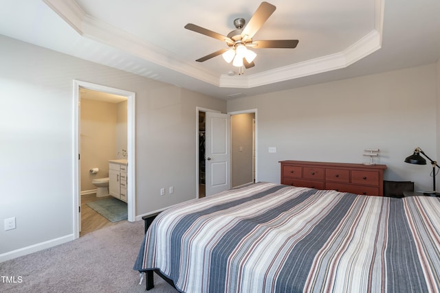 bedroom with connected bathroom, crown molding, baseboards, a tray ceiling, and light carpet