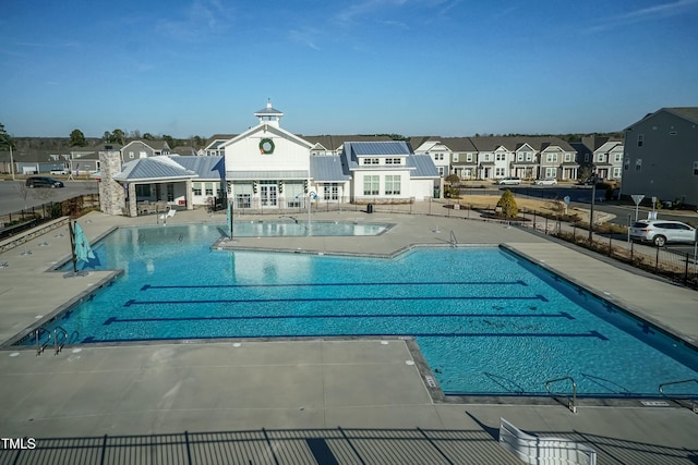 pool with a patio area, a residential view, and fence