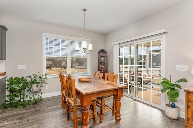 dining area featuring a notable chandelier, baseboards, and wood finished floors