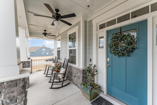 property entrance with stone siding, covered porch, and ceiling fan