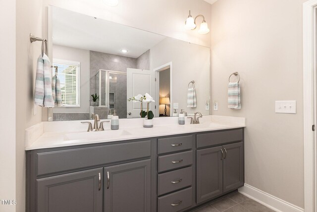 bathroom featuring double vanity, a shower stall, baseboards, and a sink