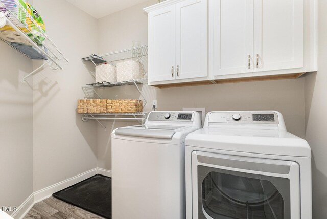 laundry room with wood finished floors, cabinet space, washing machine and dryer, and baseboards