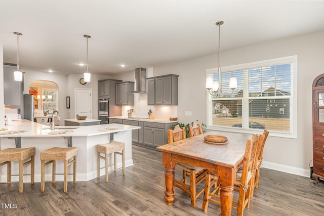 dining space featuring arched walkways, recessed lighting, dark wood finished floors, and baseboards