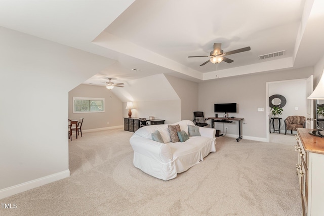 living area featuring a tray ceiling, a ceiling fan, and visible vents