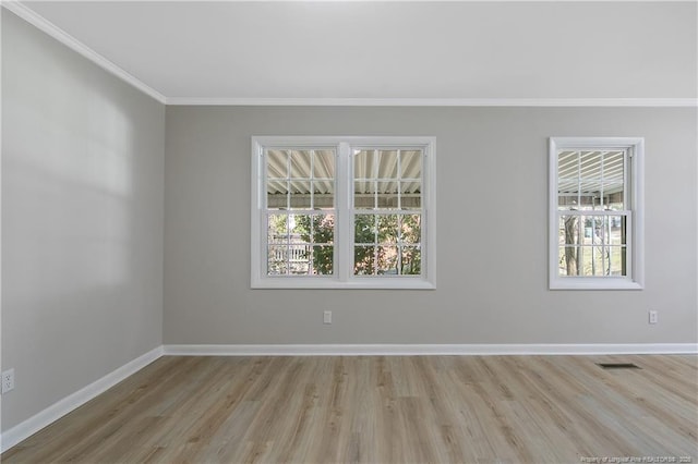 spare room featuring wood finished floors, visible vents, baseboards, and ornamental molding