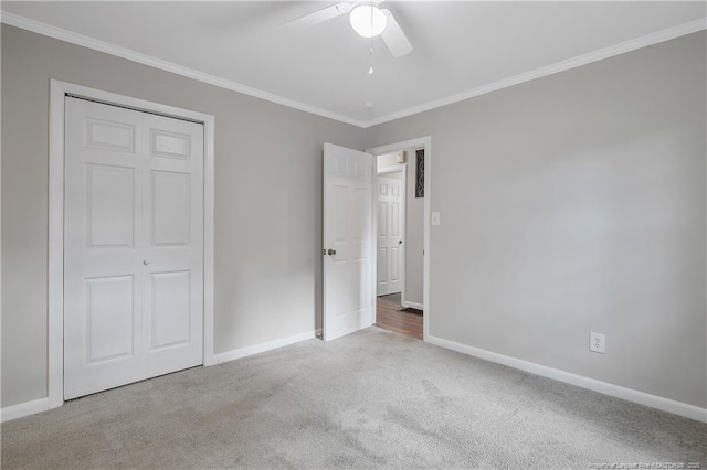 unfurnished bedroom featuring crown molding, carpet flooring, a ceiling fan, and baseboards