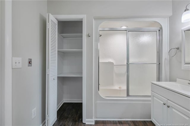 bathroom with combined bath / shower with glass door, a closet, wood finished floors, and vanity