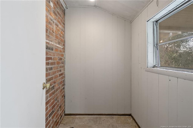 spare room with lofted ceiling and brick wall