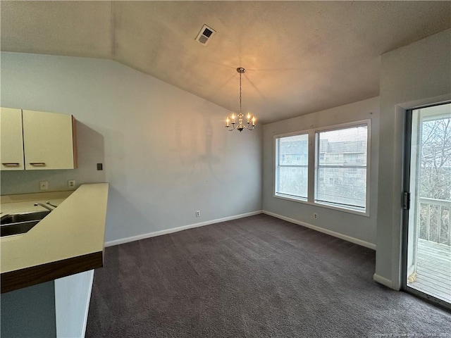 unfurnished dining area with visible vents, lofted ceiling, a sink, a notable chandelier, and dark colored carpet