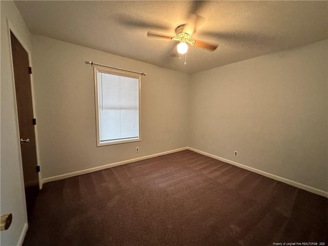 unfurnished room featuring baseboards, a textured ceiling, and dark carpet