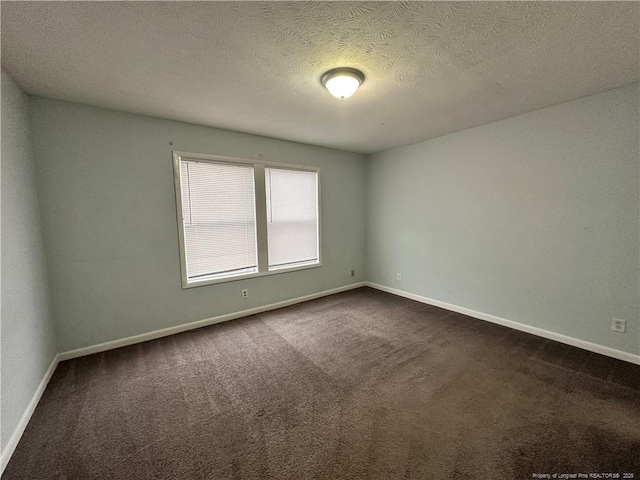 empty room with baseboards, a textured ceiling, and dark carpet