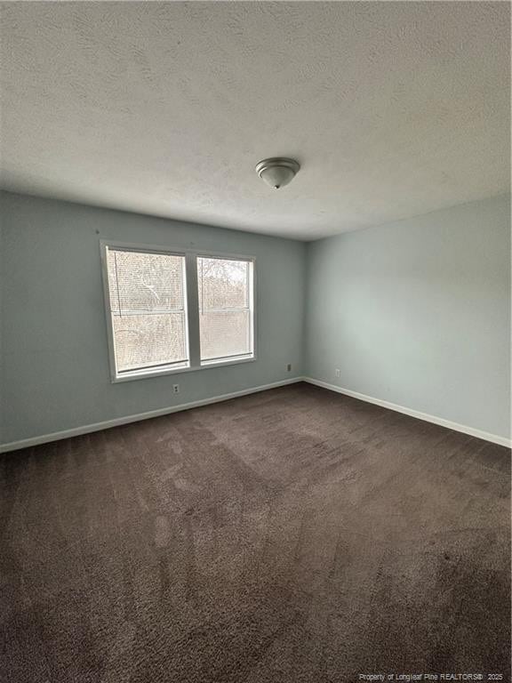 empty room with baseboards, a textured ceiling, and dark carpet