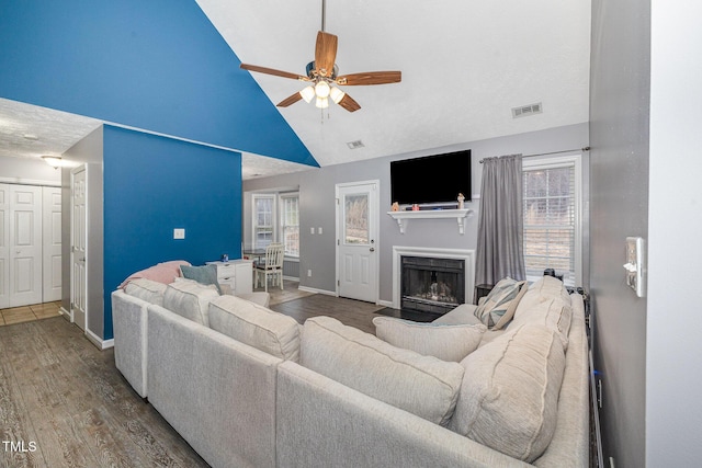 living area with visible vents, baseboards, a fireplace, wood finished floors, and a ceiling fan