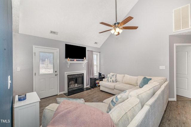 living room with visible vents, ceiling fan, a fireplace with flush hearth, and wood finished floors