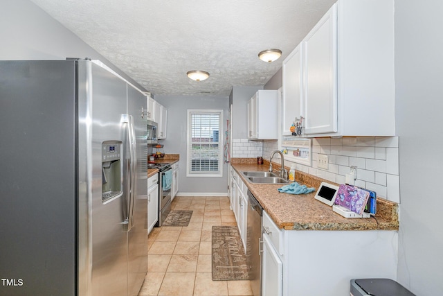 kitchen featuring a sink, backsplash, a textured ceiling, white cabinetry, and appliances with stainless steel finishes