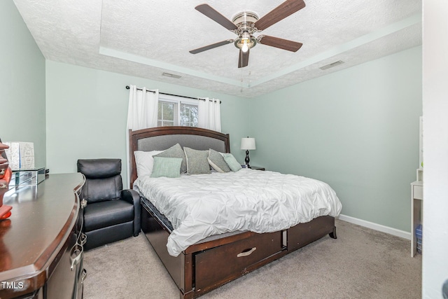 carpeted bedroom featuring a tray ceiling, baseboards, a textured ceiling, and visible vents