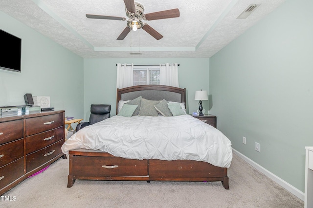 bedroom featuring a tray ceiling, baseboards, light colored carpet, and a textured ceiling