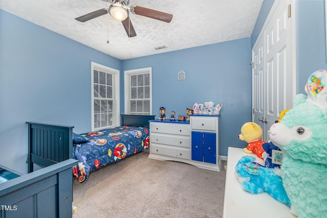 bedroom with visible vents, carpet floors, a closet, a textured ceiling, and a ceiling fan