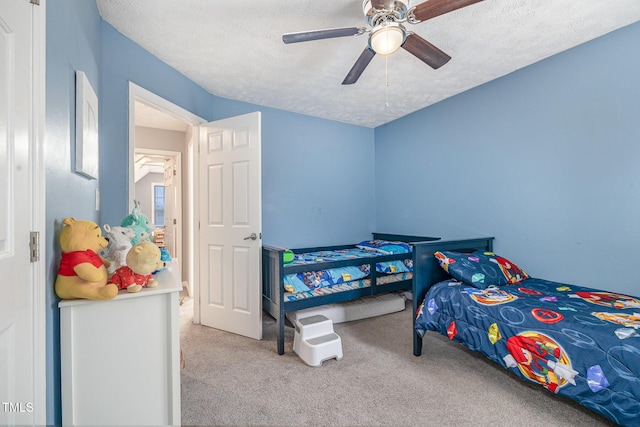 carpeted bedroom featuring a ceiling fan and a textured ceiling