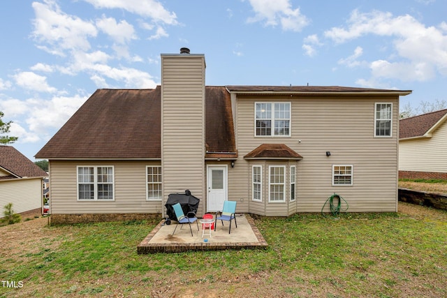 rear view of house with a patio, a yard, and a chimney